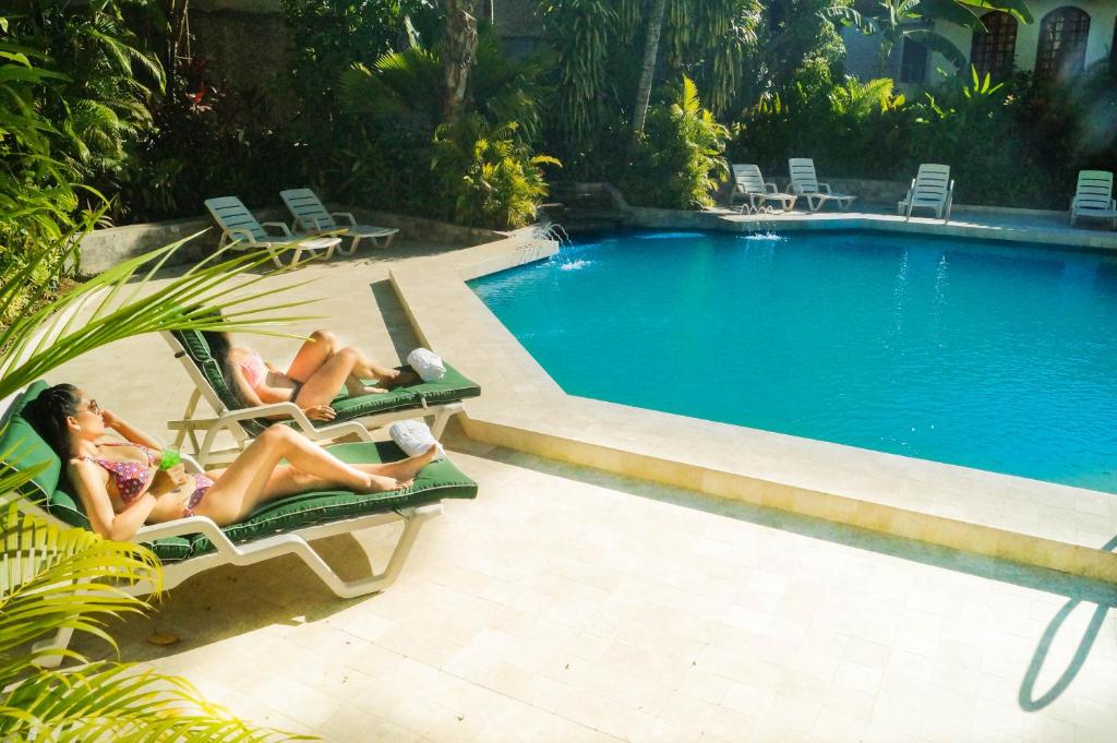 dos mujeres tumbadas en sillas de jardín junto a una piscina en Grand Hotel Mercedes en Pucallpa