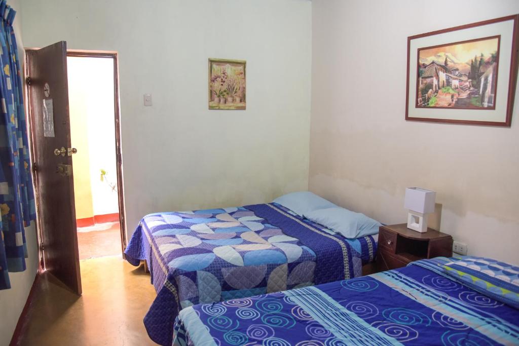 una camera con due letti e una porta per una stanza di Brabant Hostal a Nazca