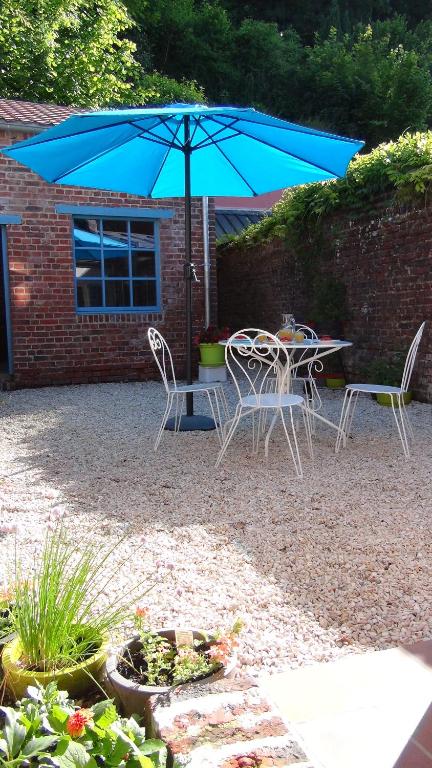 a table and chairs with a blue umbrella at Chez Louise in Guise