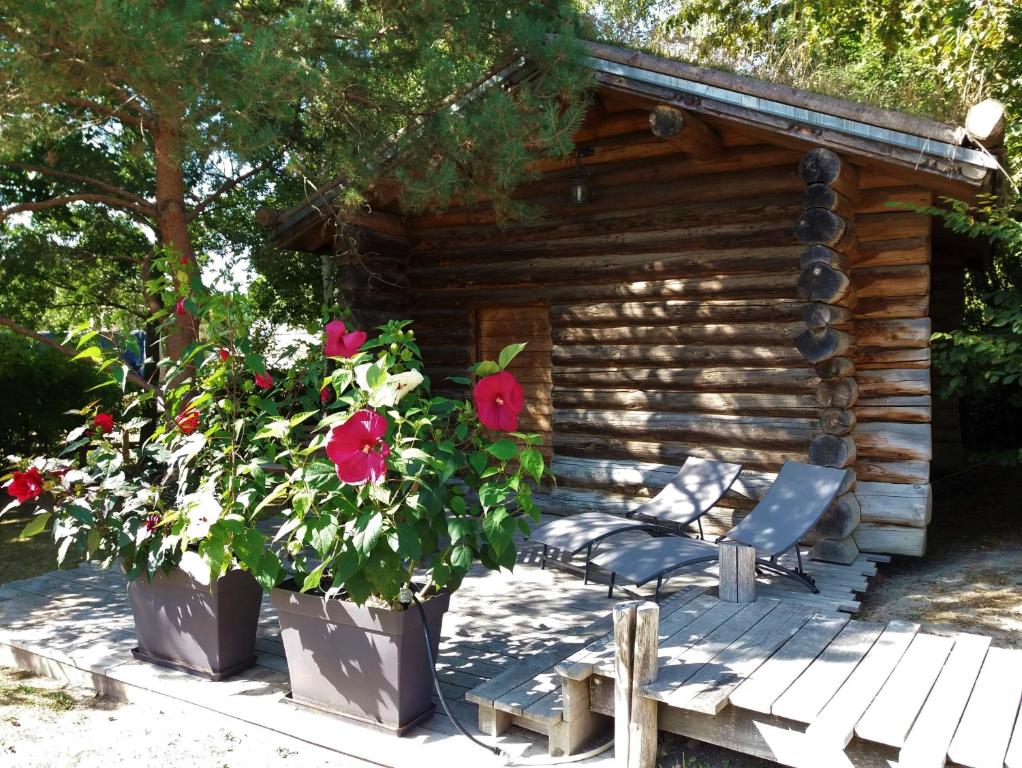 a wooden cabin with a chair and flowers in front of it at Log Cabin in the Loire Valley in Ambillou-Château