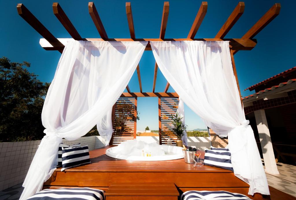 a gazebo with white curtains and a table at Mar e Mar Florianópolis in Florianópolis