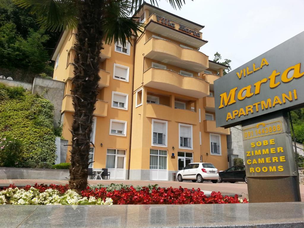 a sign in front of a building with a palm tree at Apartments Villa Marta in Opatija