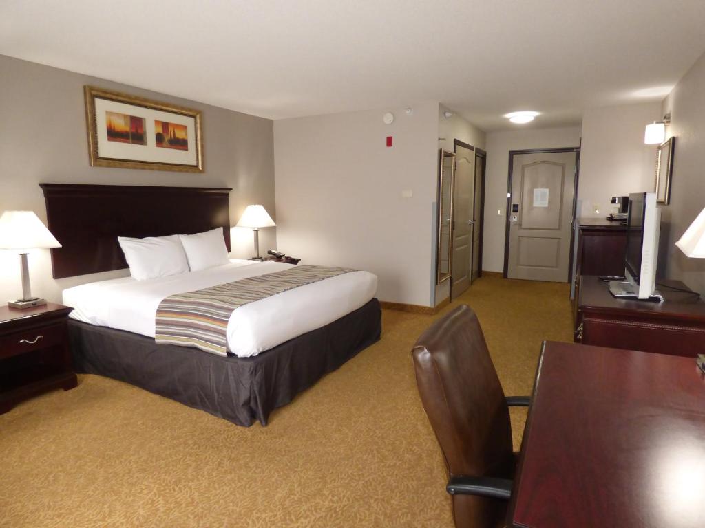 a hotel room with a bed and a desk and a table at Country Inn & Suites by Radisson, Pensacola West, FL in Pensacola