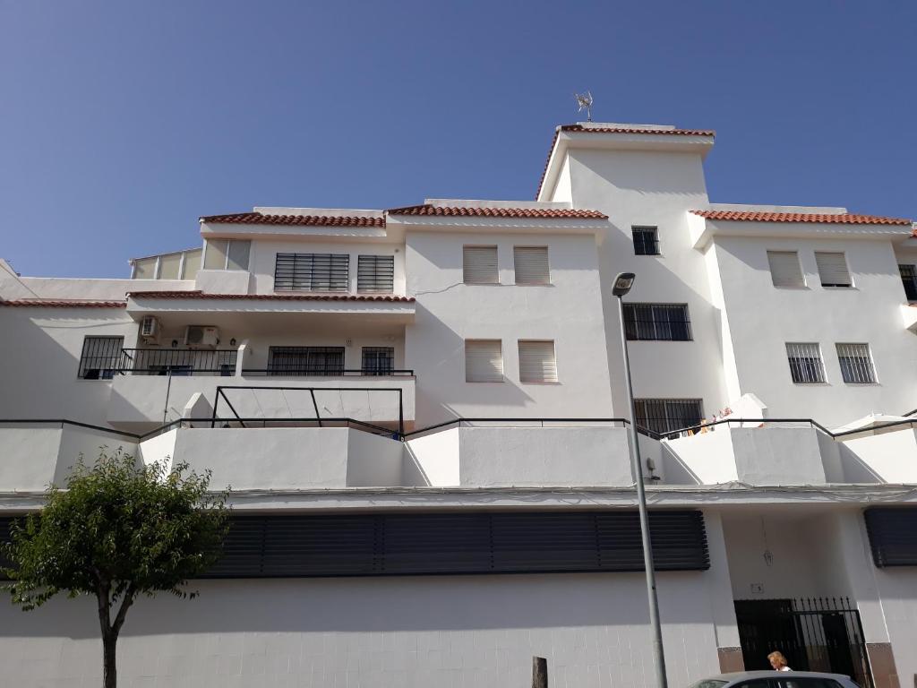 un edificio blanco con un árbol delante en El Marinero, en Rota