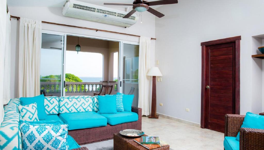 uma sala de estar com um sofá azul e uma varanda em Rio Dulce Ocean View Penthouse V-13 em Iguana