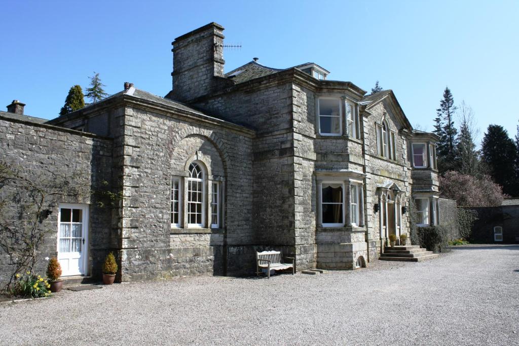 an old stone house with a bench in front of it at The Rochester Wing Orton Hall in Orton