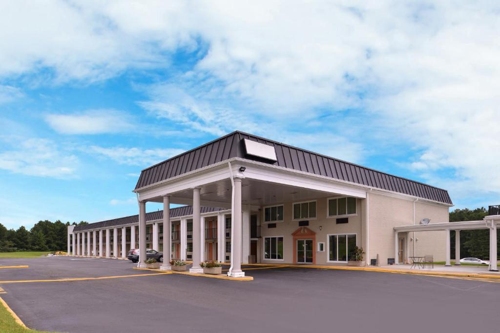 a large white building with a parking lot at Americas Best Value Inn Richmond South in Richmond