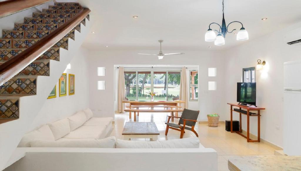 a living room with white furniture and a staircase at Town House 6 in Iguana