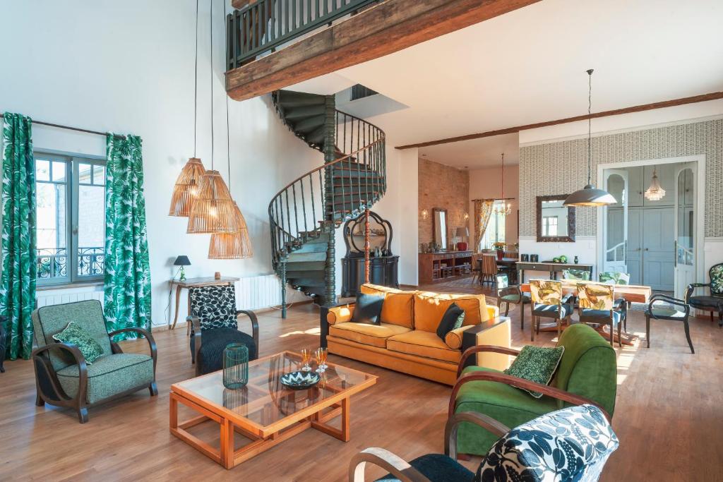 a living room filled with furniture and a spiral staircase at Chai du Chateau de Morteuil in Merceuil