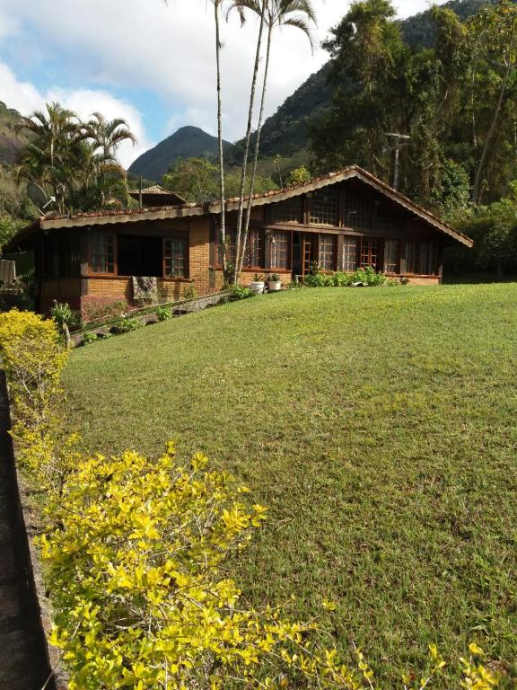 uma casa com um campo em frente em Canto da serrinha em Teresópolis