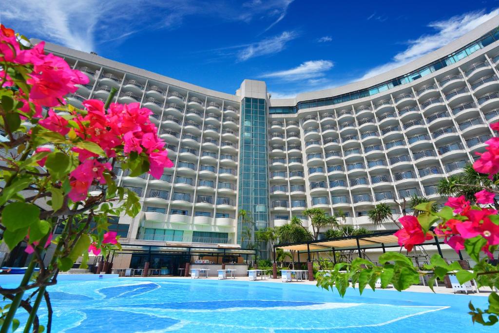 a large hotel with pink flowers in front of it at Loisir Hotel Naha in Naha