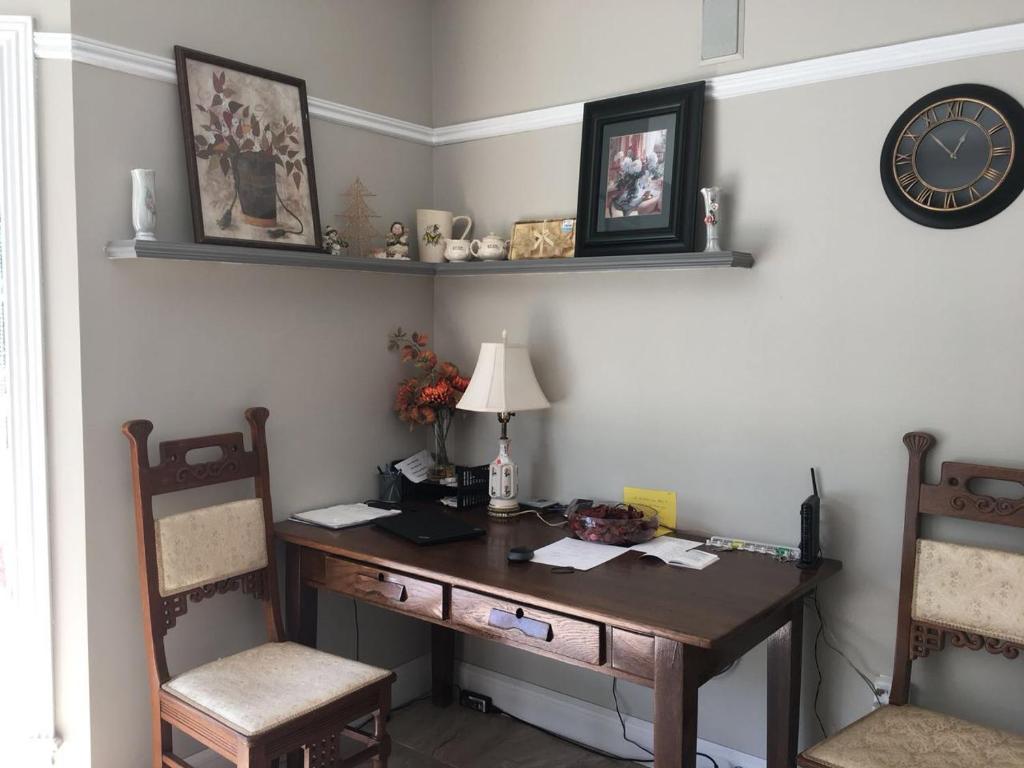 a desk with two chairs and a clock on a wall at Seaview White House in Stratford