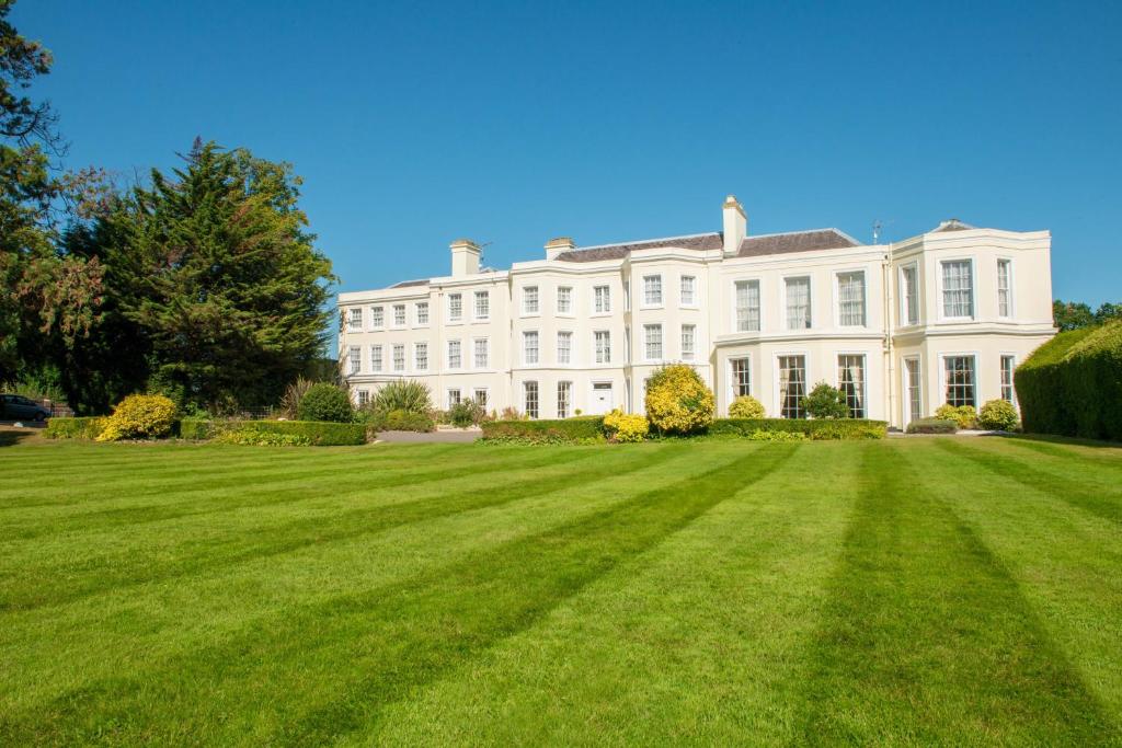 uma grande casa branca com um grande jardim relvado em Burnham Beeches Hotel em Slough