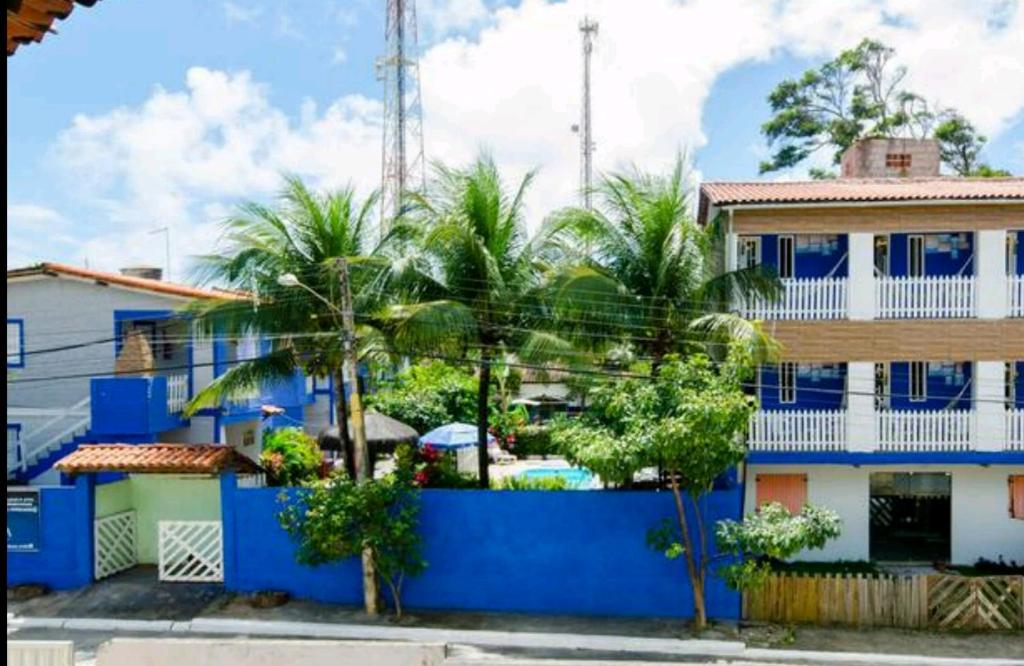 a blue building with palm trees in front of it at Chalés Caiçara Serrambi in Porto De Galinhas