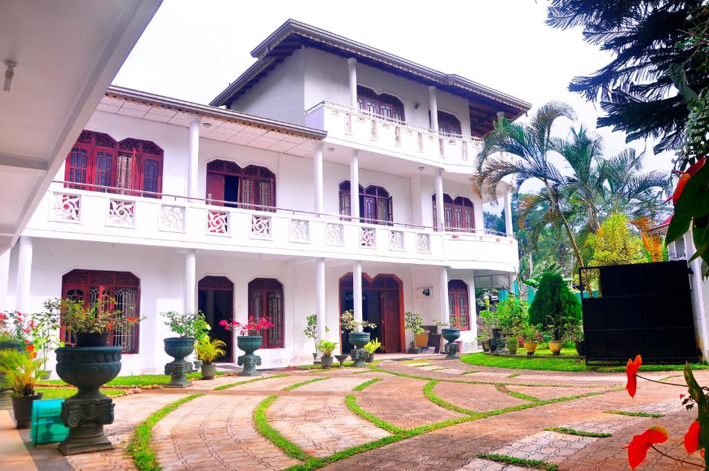 a white house with a courtyard in front of it at Power Zone Guest House in Matale