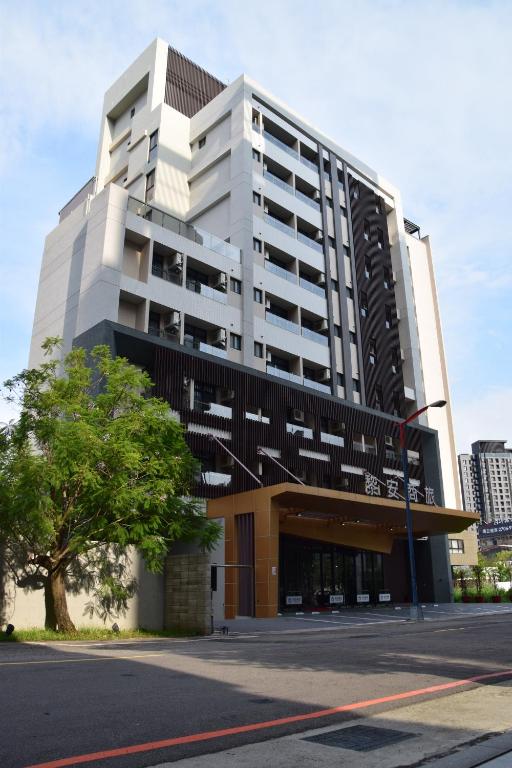 um grande edifício branco com uma árvore em frente em LIANN Hotel em Taichung