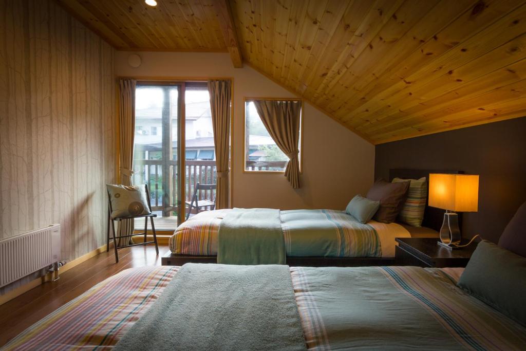 a hotel room with two beds and a window at Hakuba Powder Cottage in Hakuba
