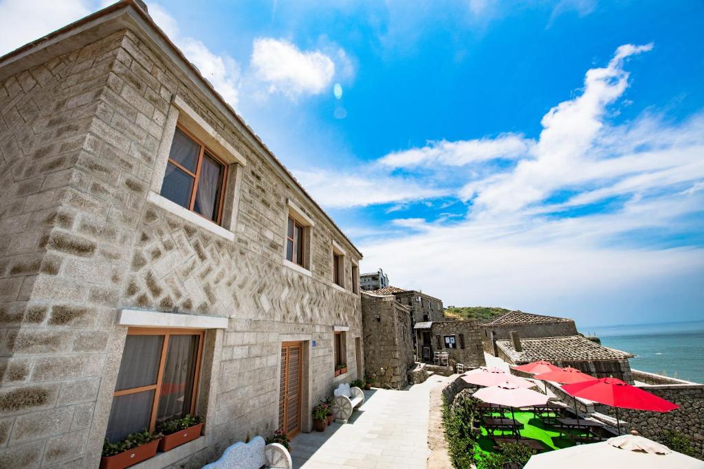 a building with tables and umbrellas next to the ocean at Just Coffee Hostel 5 in Beigan