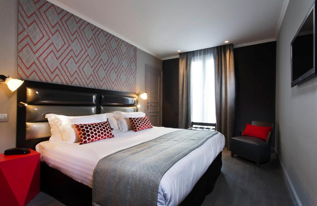 パリにあるオテル ガランスの大きなベッドと椅子が備わるホテルルームです。