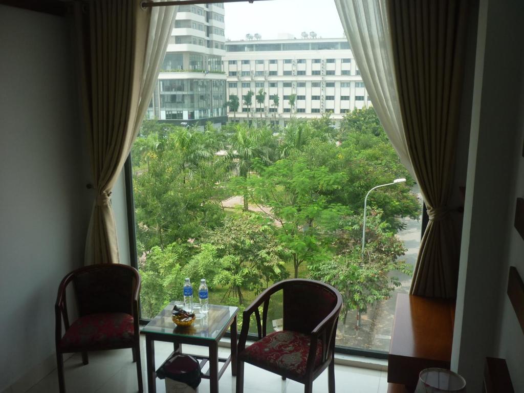 Habitación con mesa, sillas y ventana grande. en Asia Apartment Hotel Bac Ninh, en Bắc Ninh