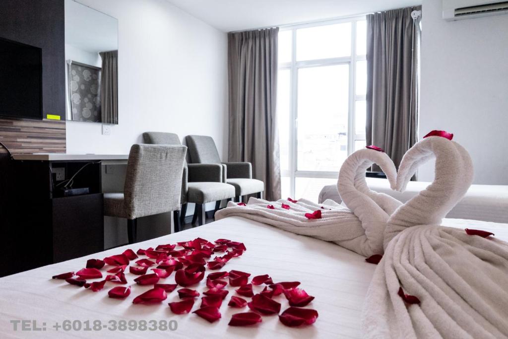 Dois cisnes numa cama com rosas. em Classy Studio Apartment (KBCP) em Kota Bharu