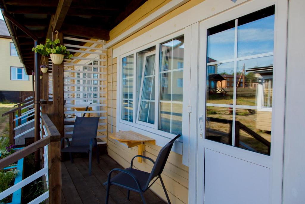 a porch with chairs and a table and a door at Хотэй in Khuzhir