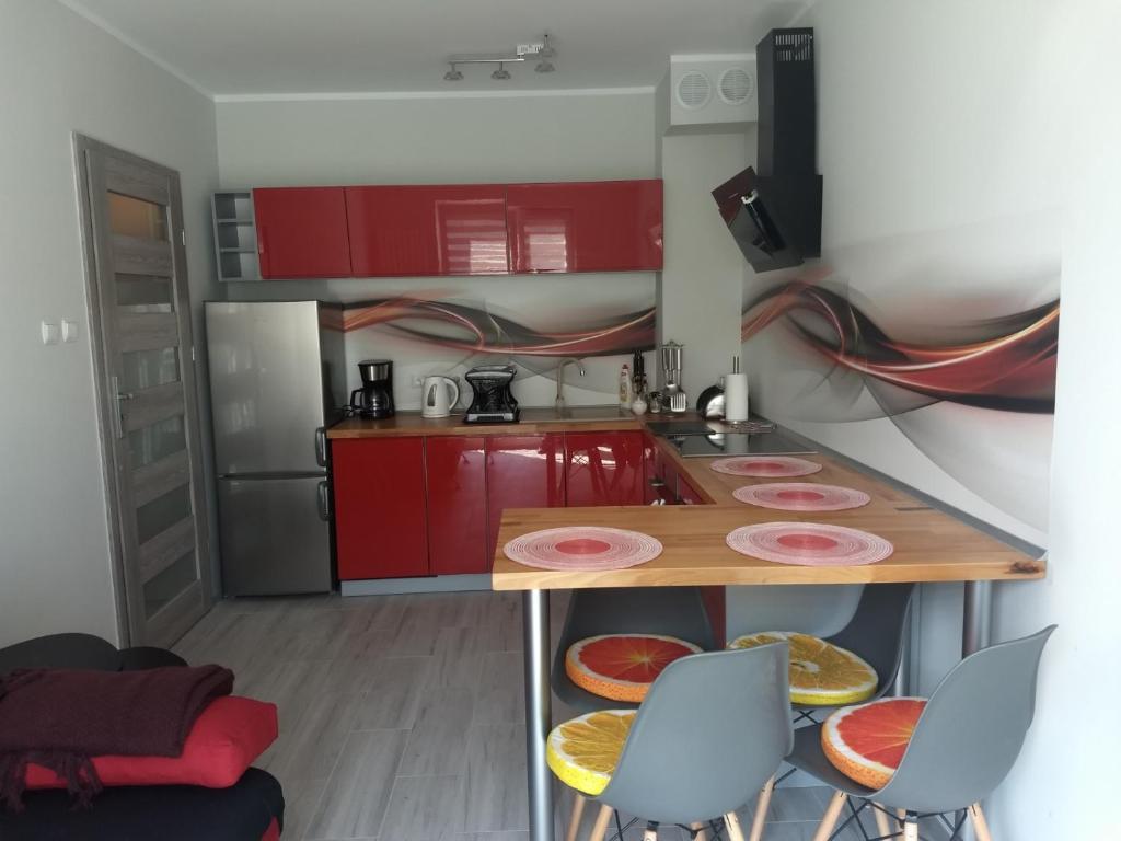 une cuisine avec des armoires rouges et une table et des chaises dans l'établissement Apartament Sunny Day, à Polanica-Zdrój