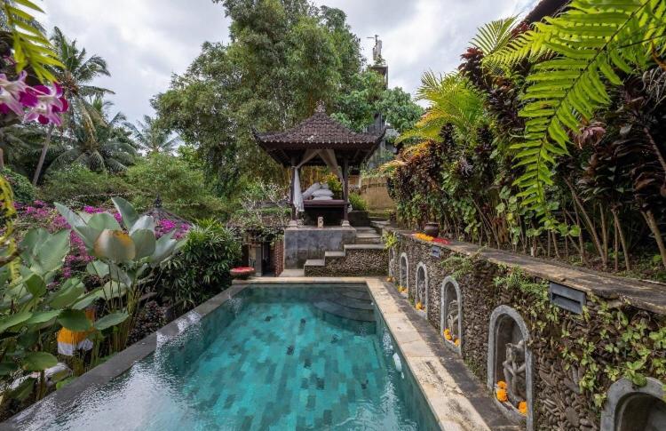 a swimming pool in a garden with a gazebo at Rumah Kelinci in Ubud