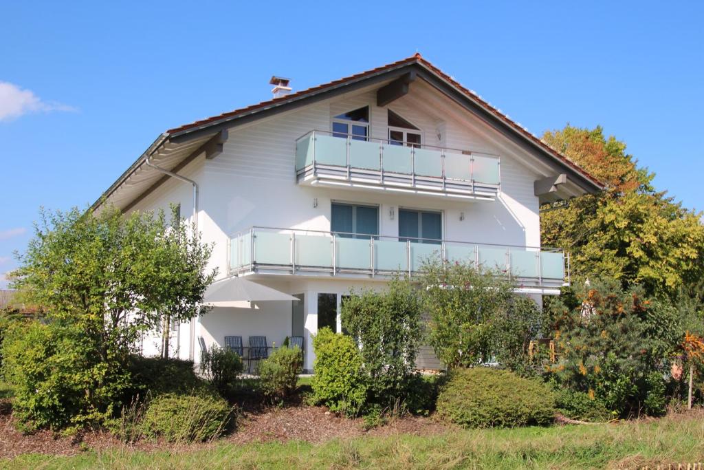 a white house with a balcony on the side of it at Chiemsee-Edelweiß Ferienwohnung in Prien am Chiemsee