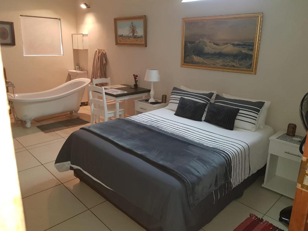 a bedroom with a bed and a bathtub and a bed and a bathroom at Tzaneen White House Lodge in Tzaneen
