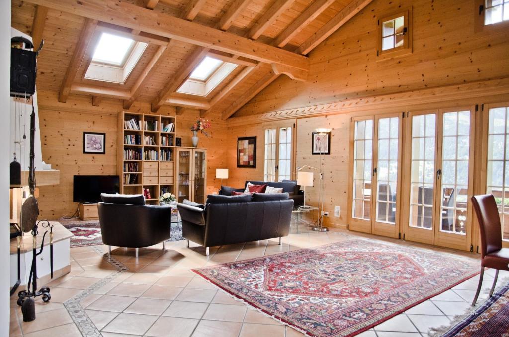 a living room with wooden ceilings and a living room with furniture at Chalet Heimat - GRIWA RENT AG in Grindelwald