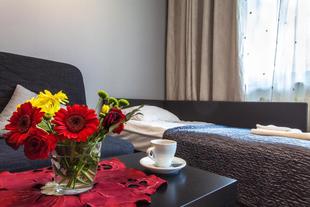un jarrón de flores en una mesa junto a una cama en Batory Apartament, en Chorzów