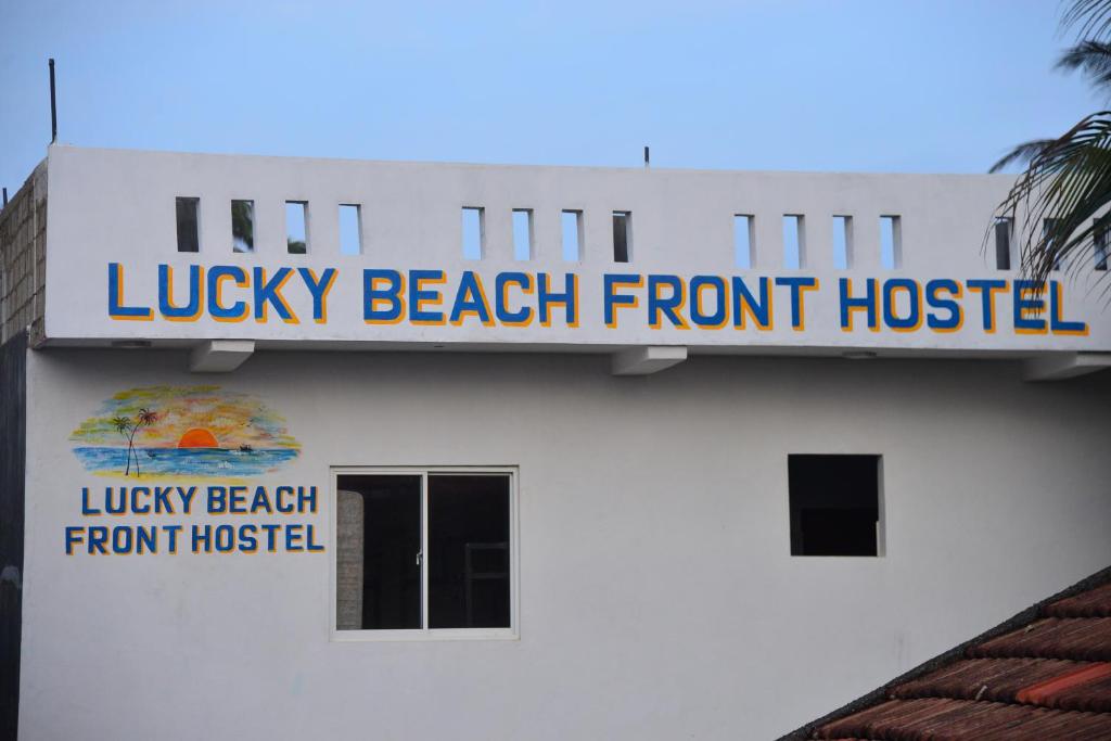 a building with a sign that reads lucky beach front hotel at Lucky Beach Front Hostel in Hikkaduwa