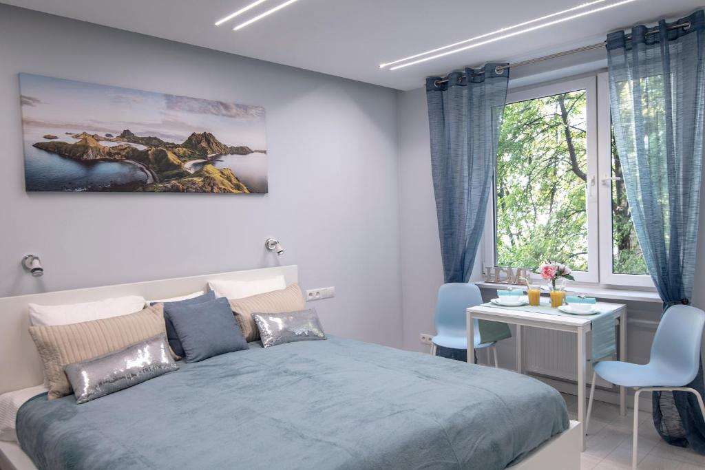 a bedroom with a bed and a table and a window at WLR Apartments - Hoza I in Warsaw