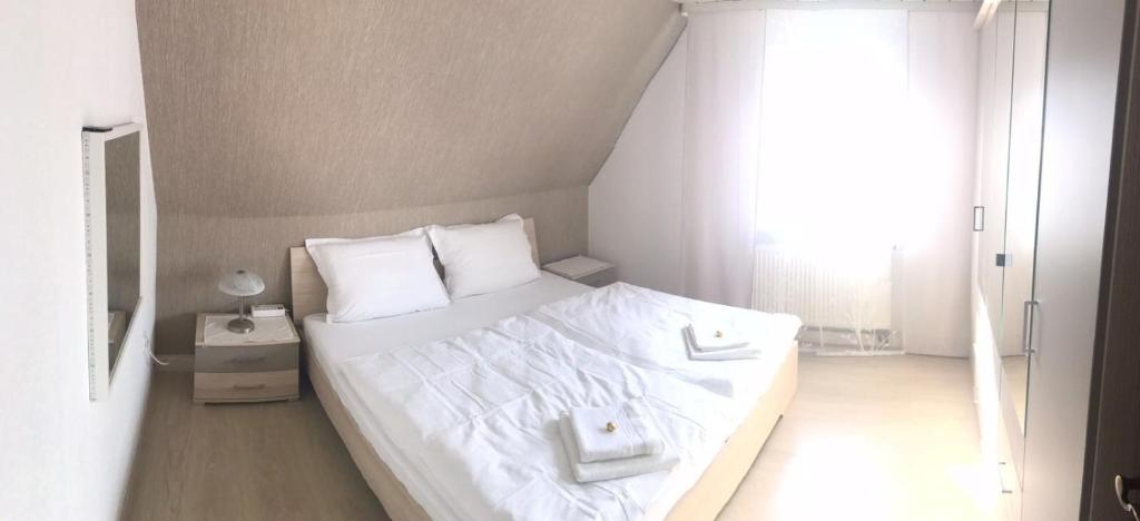 Cama blanca en habitación con ventana en Ferienwohnung Eislingen, en Eislingen