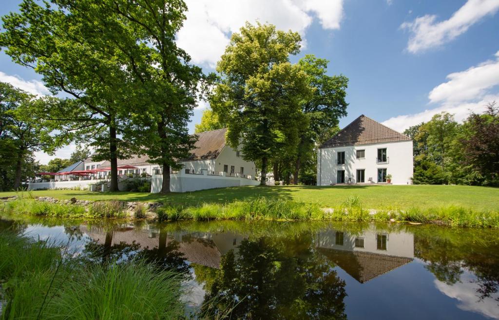 a white house with a pond in front of it at B&O Parkhotel in Bad Aibling