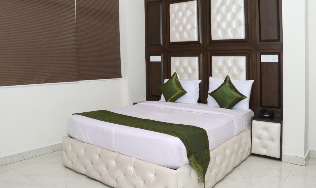 a bedroom with a large white bed with green pillows at Treebo Trend JD Residency Mohali in Chandīgarh