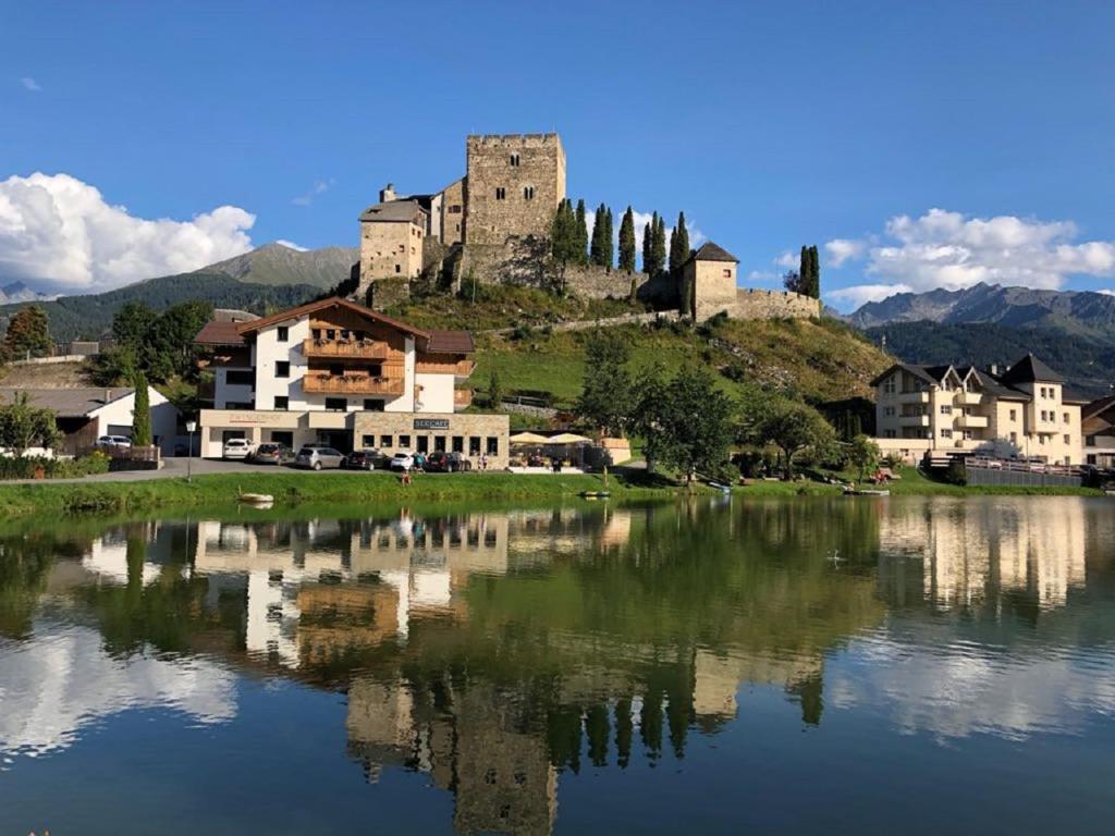 un castillo sentado en la cima de una colina junto a un lago en Apart Zwingerhof, en Ladis