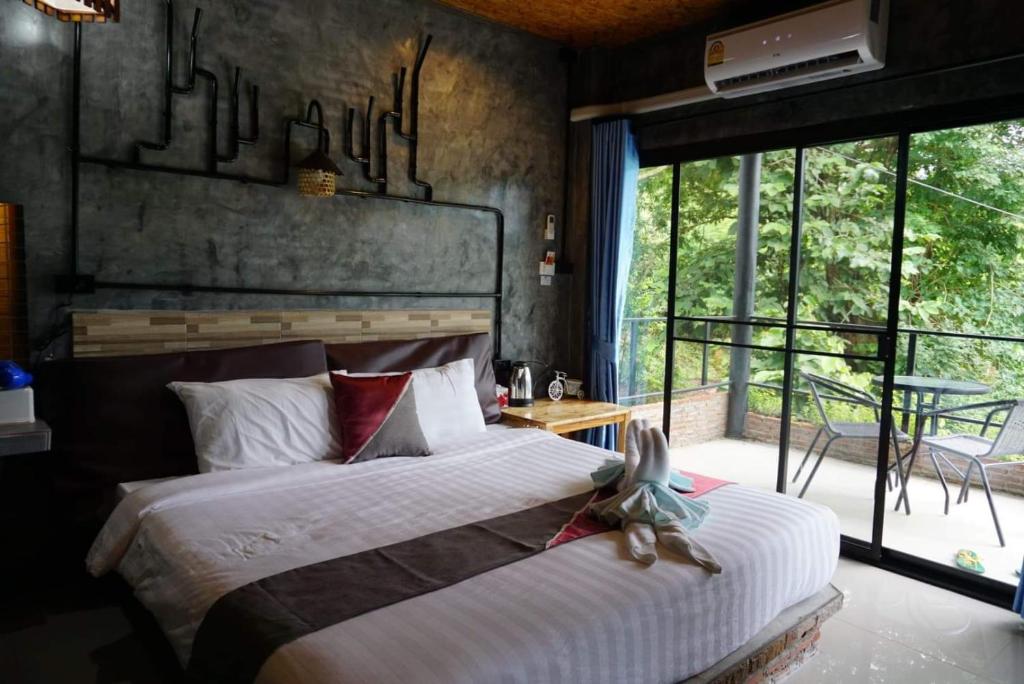 a bedroom with a bed and a large window at Keeree Loft Resort in Thong Pha Phum