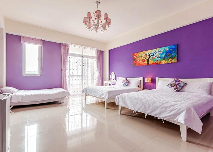 a bedroom with two beds and a purple wall at Eik Forest B&amp;B in Taitung City