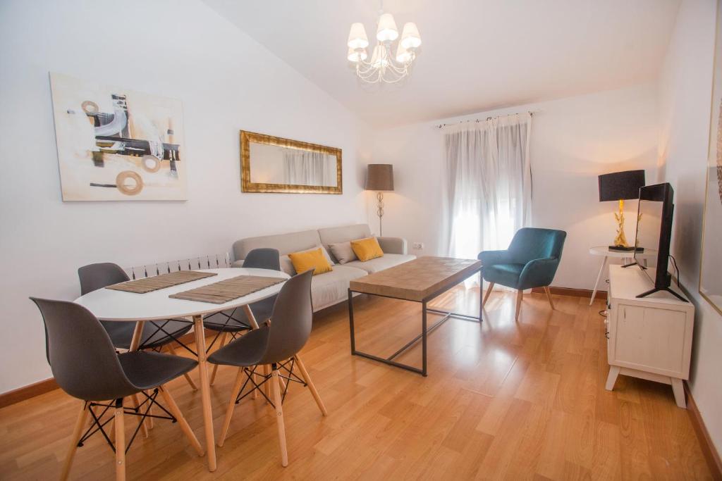 una sala de estar con un sofá, una mesa y sillas en Apartamentos Soho Boutique Plaza Mayor Caceres, en Cáceres
