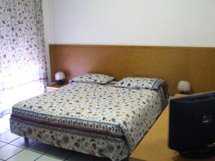 1 dormitorio con 1 cama con cabecero de madera en hotelverbania, en Sabaudia