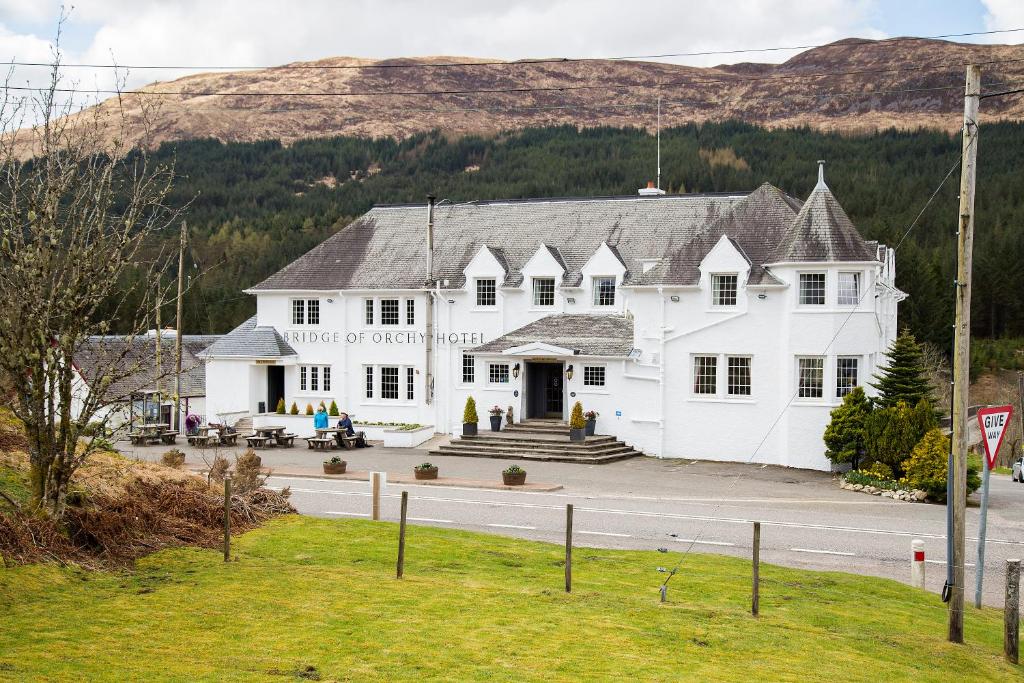 a large white building on the side of a road at Bridge of Orchy Hotel in Bridge of Orchy