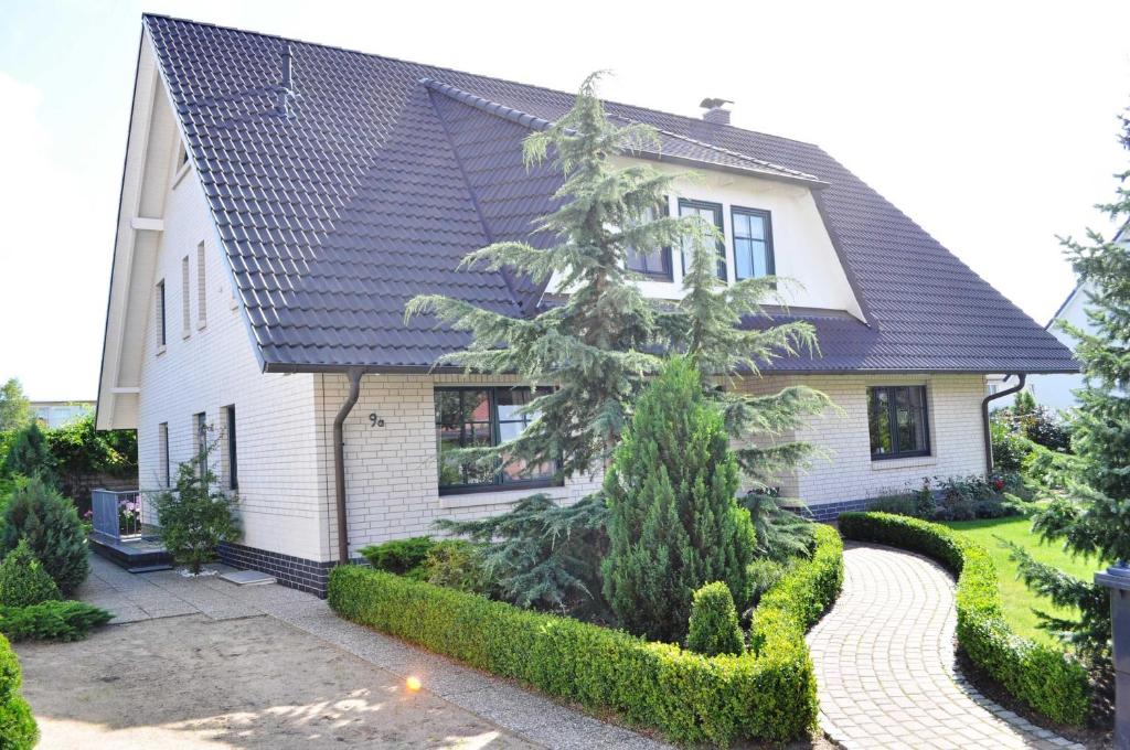 a white house with a black roof at Appartement Muschelkoje in Ostseebad Karlshagen