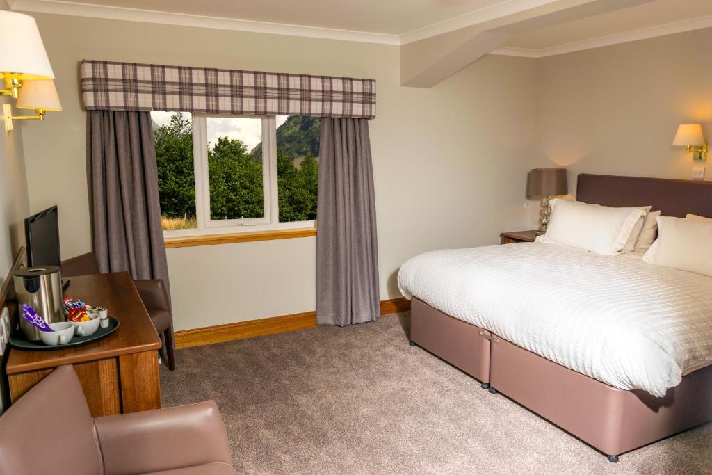 a bedroom with a large bed and a large window at Tyndrum Lodges in Tyndrum