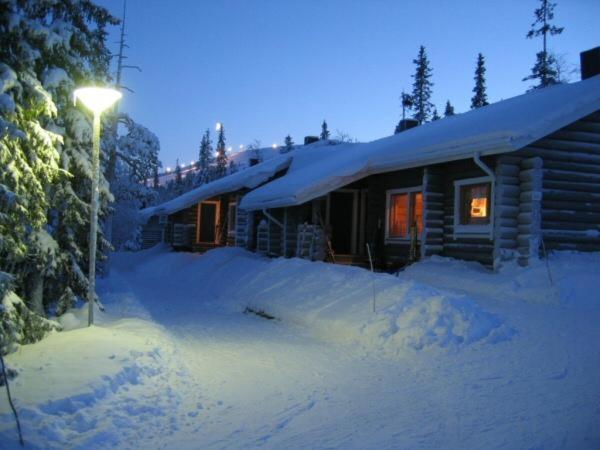 a log cabin with a light in the snow at Olosloisto Lomat in Muonio