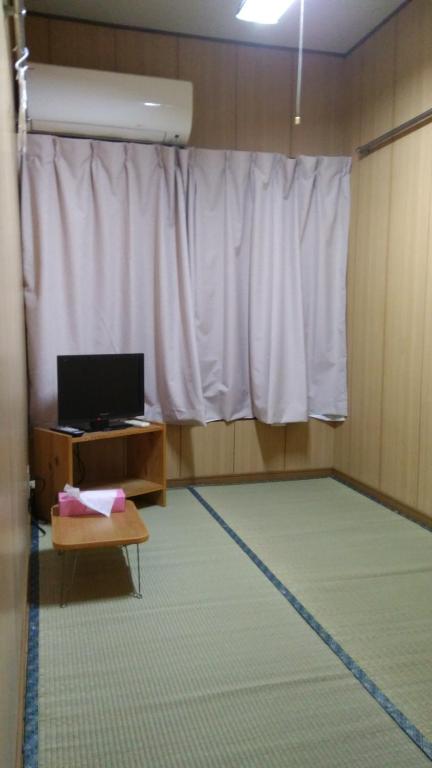 a room with a white curtain and a table and a laptop at Ryokan Nakadaya in Tokyo