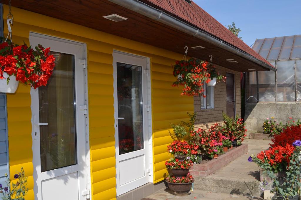 a yellow house with flowers in front of it at Ziedu pasaule in Krāslava