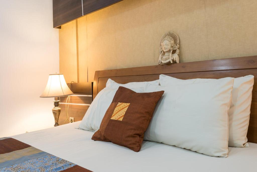 a bed with white pillows and a headboard with a statue at Villa Melasti Wardana in Uluwatu