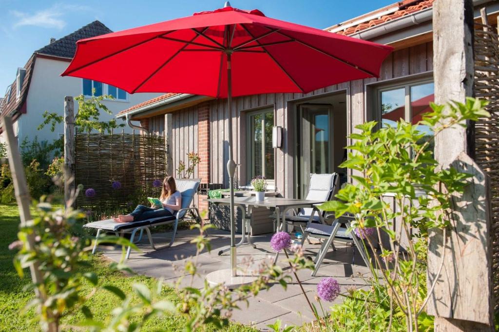 a woman sitting on a patio under a red umbrella at Ferienwohnung Spie in Sarkwitz